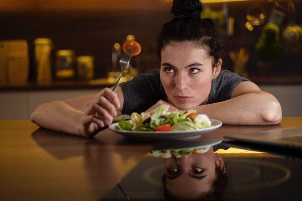 Woman sitting on a table in front of a plate full of salad